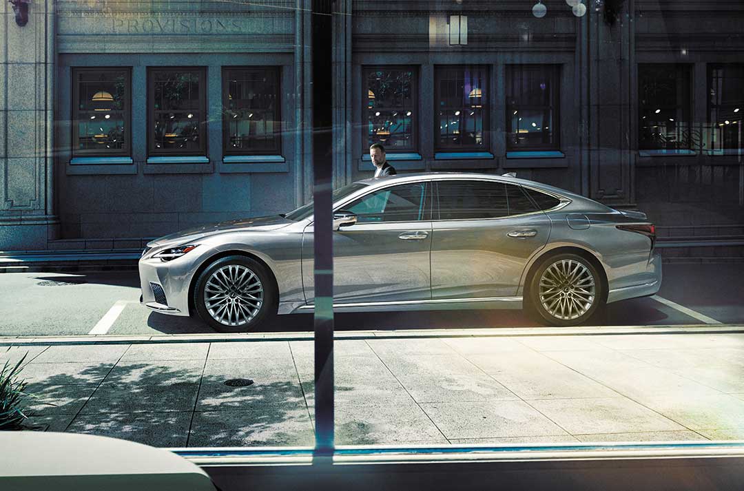 The rear, side view of a Lexus LS viewed through a cafe window.