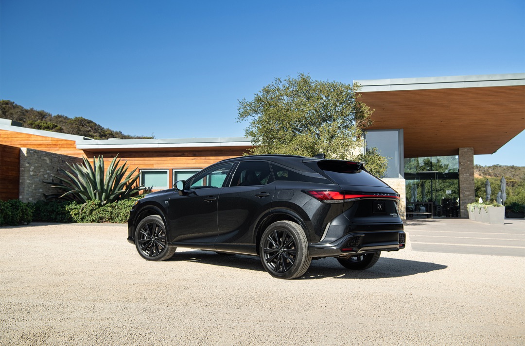 A Lexus RX 500h F Sport Performance in Graphite Black is parked on a gravel driveway